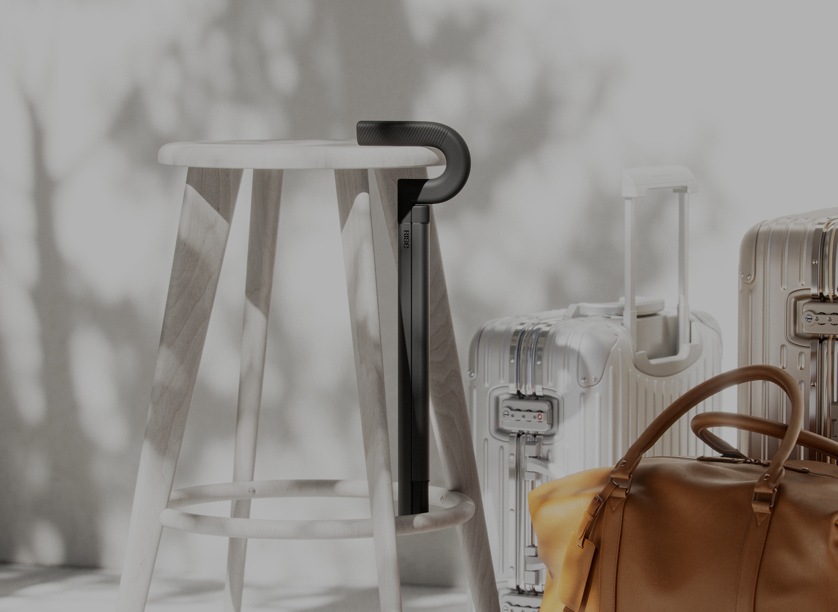 The Rise cane leaning against a wooden stool beside travel luggage