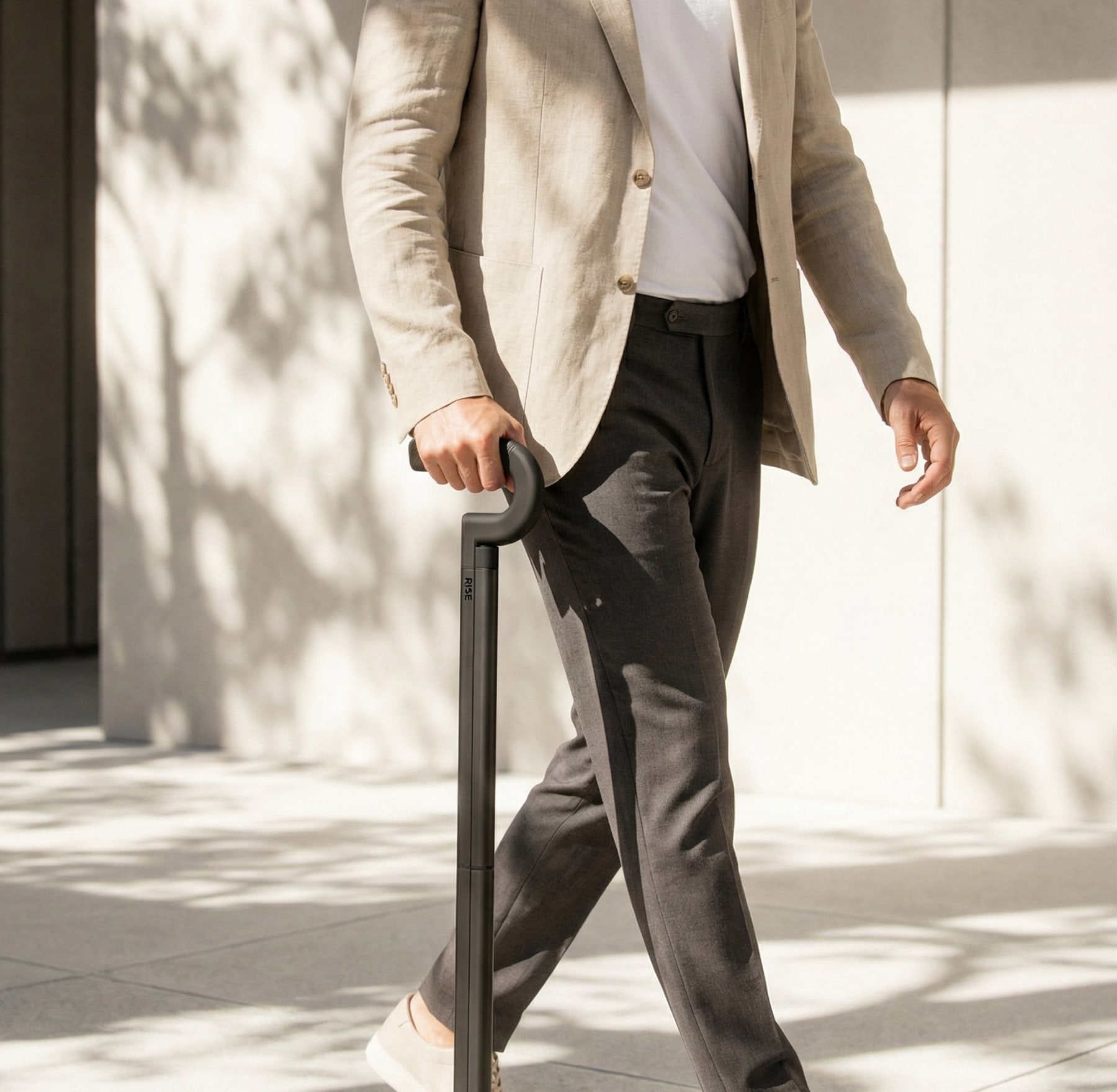 A man in a linen blazer walking with the Rise cane