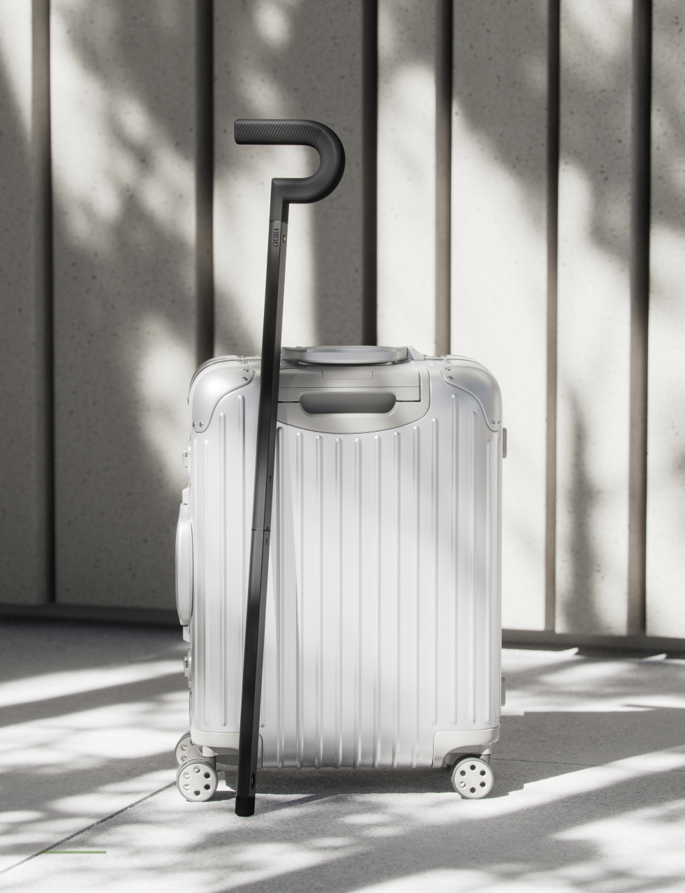 The Rise cane leaning against a silver hard-shell suitcase