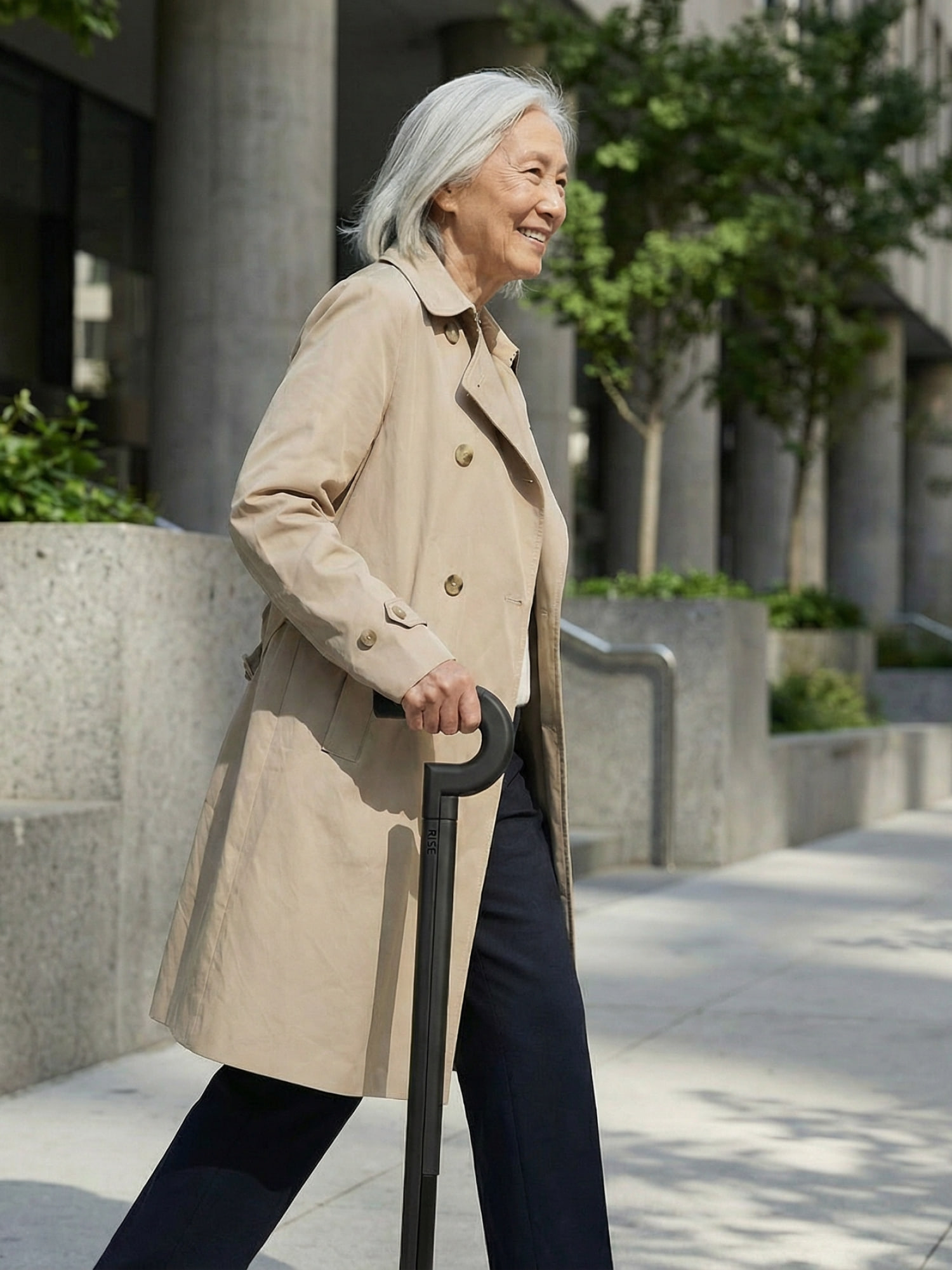A woman in a trench coat walking with the Rise cane